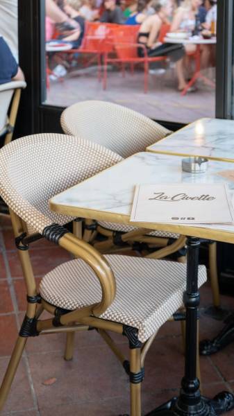 Aménagement de la terrasse du restaurant La Civette avec des tables blans marbre à Nice 