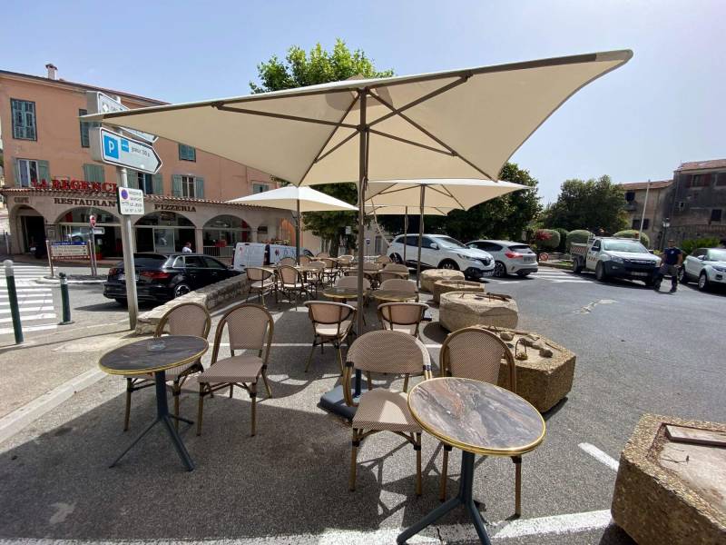 Aménagement en table, chaise et parasols de la terrasse du restaurant La Régence à la  Turbie